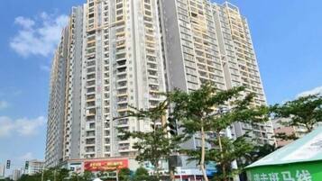 A high-rise building with multiple floors, surrounded by trees and a clear sky.
