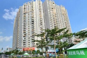 A high-rise building with multiple floors, surrounded by trees and a clear sky. - Xingqiba Business Hotel Maoming (Maoming)