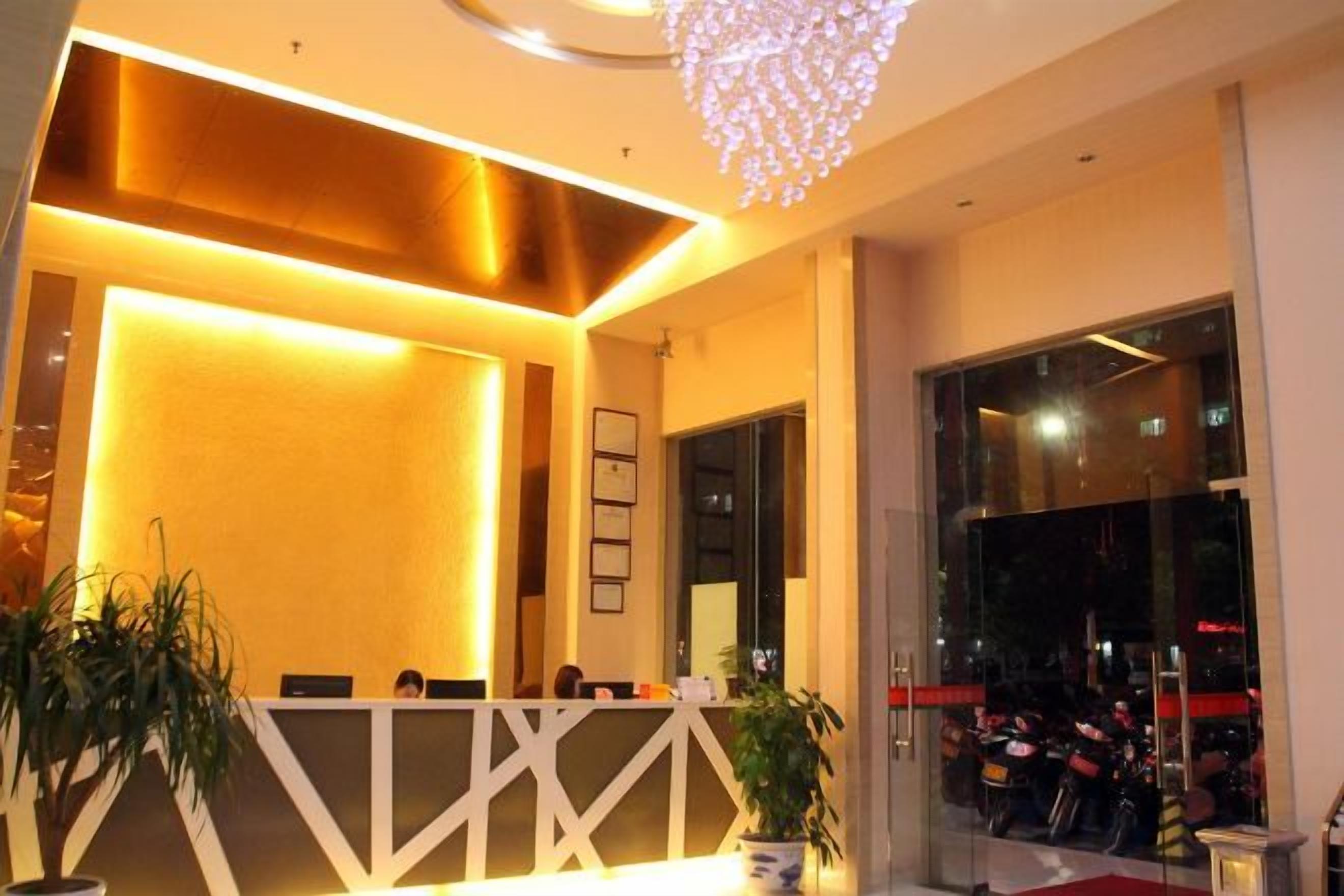 A reception area with a reception desk, potted plants, and a chandelier.