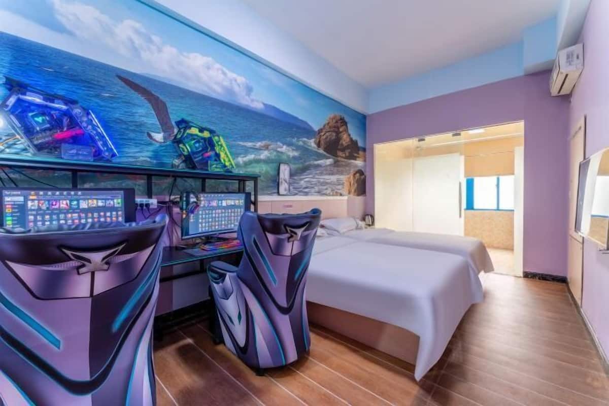 A room with a bed, a desk with a computer, and a wall mural of the ocean.