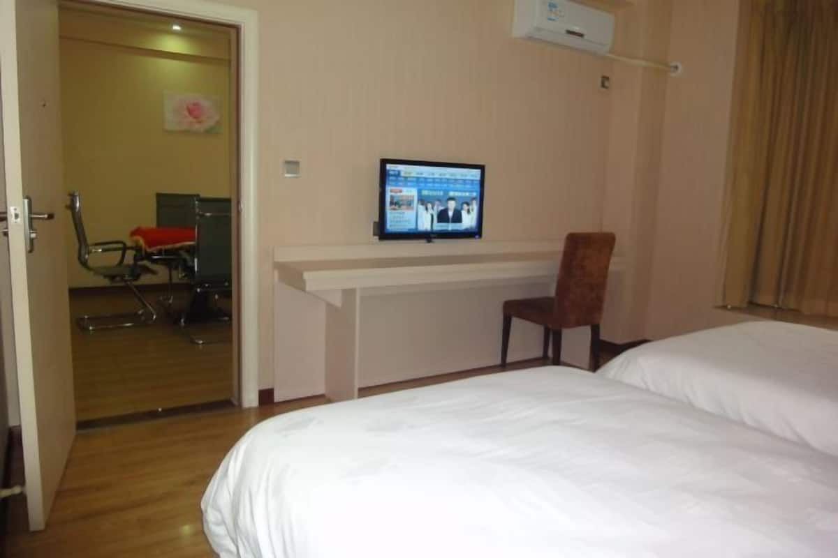 A hotel room with a bed, a desk with a computer, a chair, and a door leading to a bathroom.