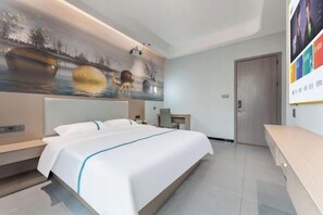 Een moderne hotelkamer met een groot bed, een bureau en een muurschildering.