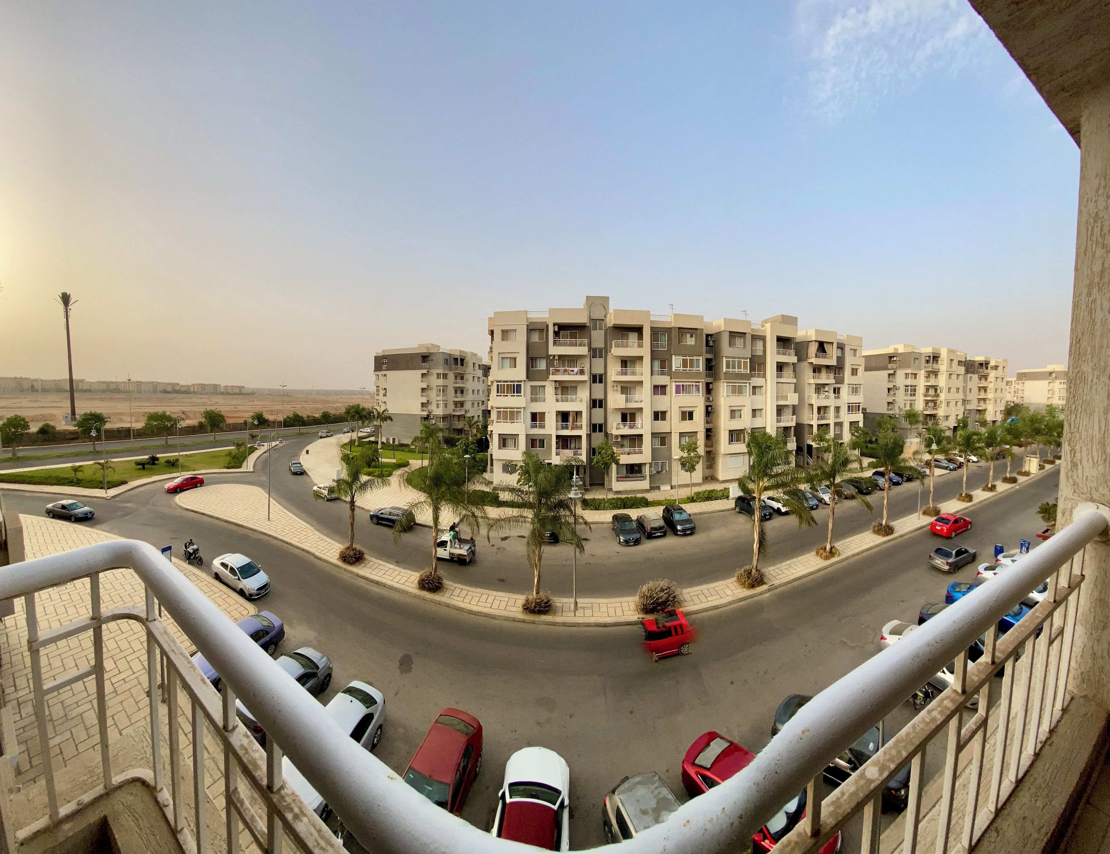 A residential area with multi-story apartment buildings, a roundabout, and parked cars.