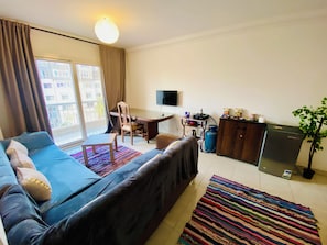 A living room with a sofa, a coffee table, a TV, a desk, and a plant. - Madinaty (New Cairo)