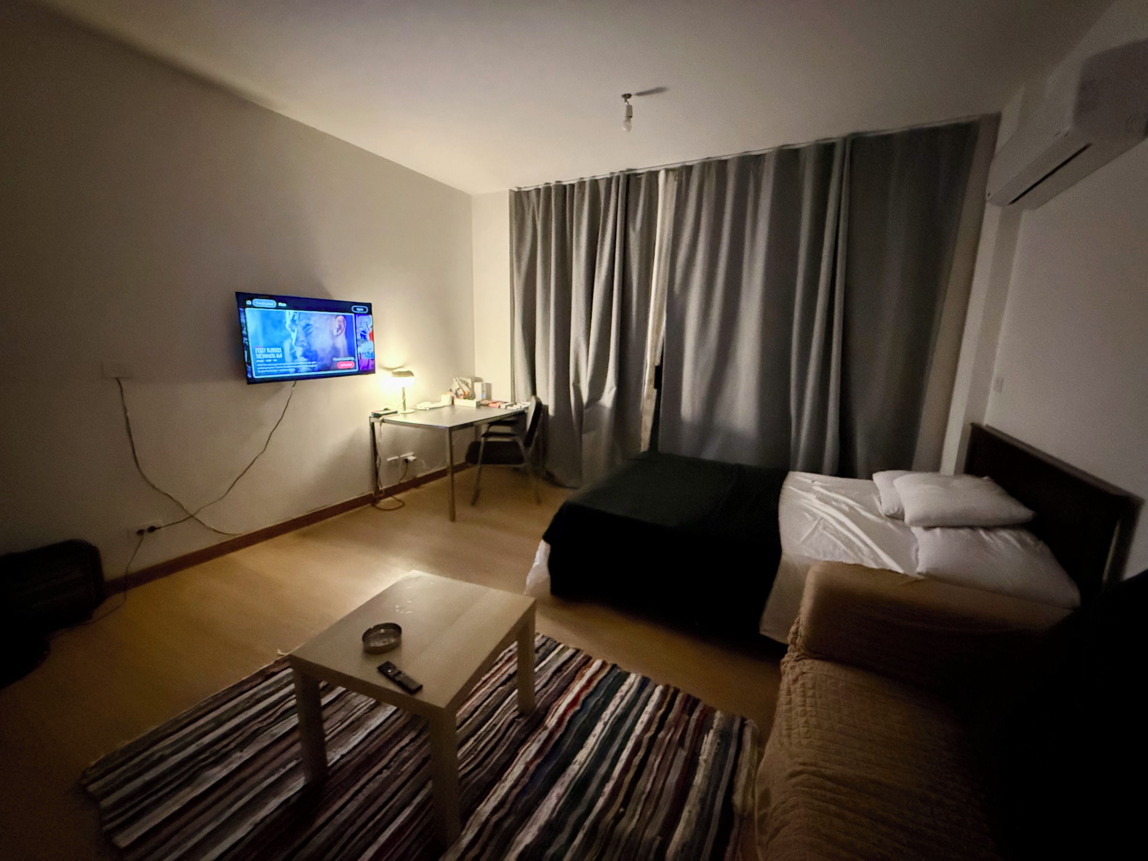 Ein Hotelzimmer mit Bett, Schreibtisch, Fernseher und einem Fenster mit Vorhängen.