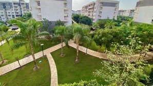 A residential complex with multiple apartment buildings, a well-maintained garden with palm trees, and a paved walkway. - Madinaty (New Cairo)