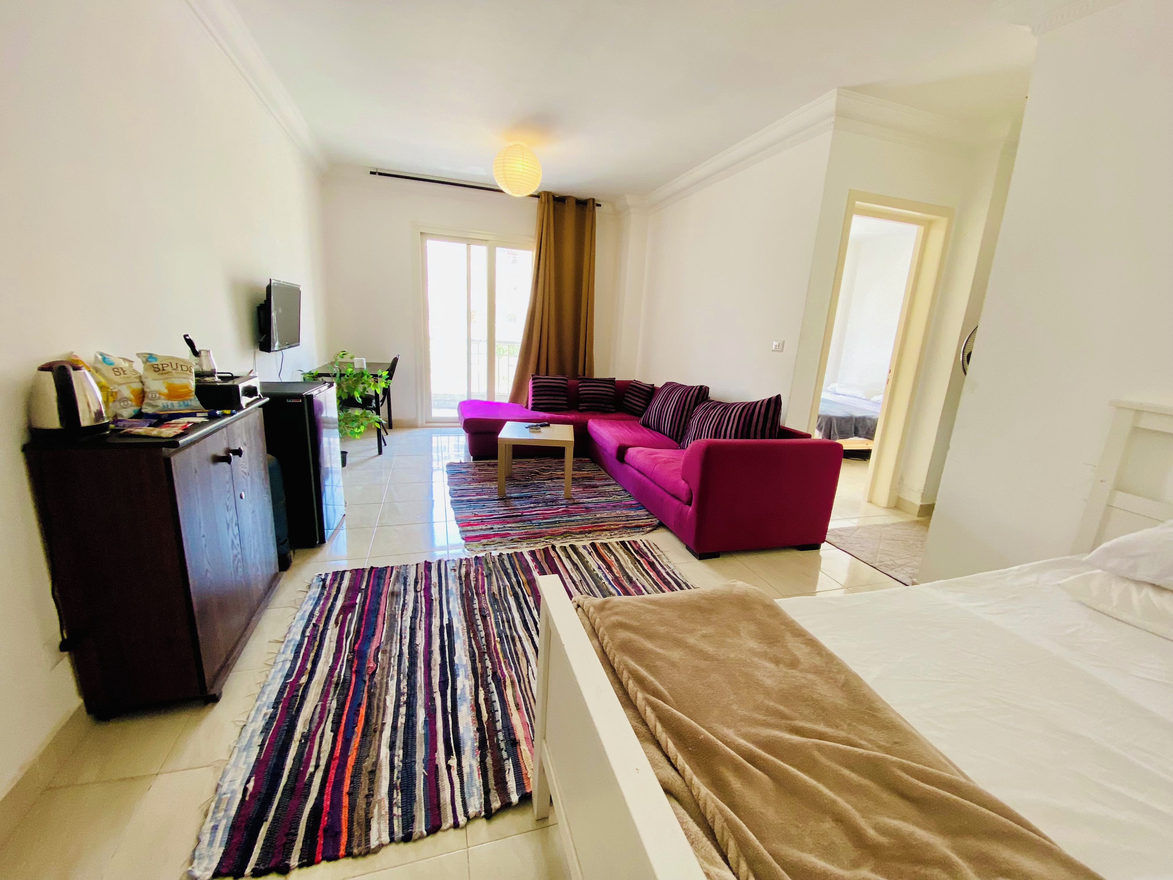 A hotel room with a bed, a sofa, a coffee table, a desk, and a television.