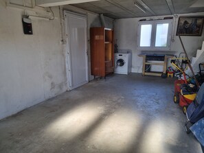 Compact room with a door, wardrobe, washing machine, and window offering a view of the outside.