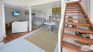 A spacious living area with a white sofa, a round table, and a wooden staircase. - Breathtaking views over Bridgewater Bay (Cape Bridgewater)