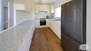 A modern kitchen with white cabinets, a stainless steel refrigerator, and a wooden floor. - Breathtaking views over Bridgewater Bay (Cape Bridgewater)