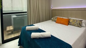A hotel room with a bed, a window with curtains, a ceiling light, and a view of the outside. - Flat Ofurô 06 VP by La Playa (Ipojuca)
