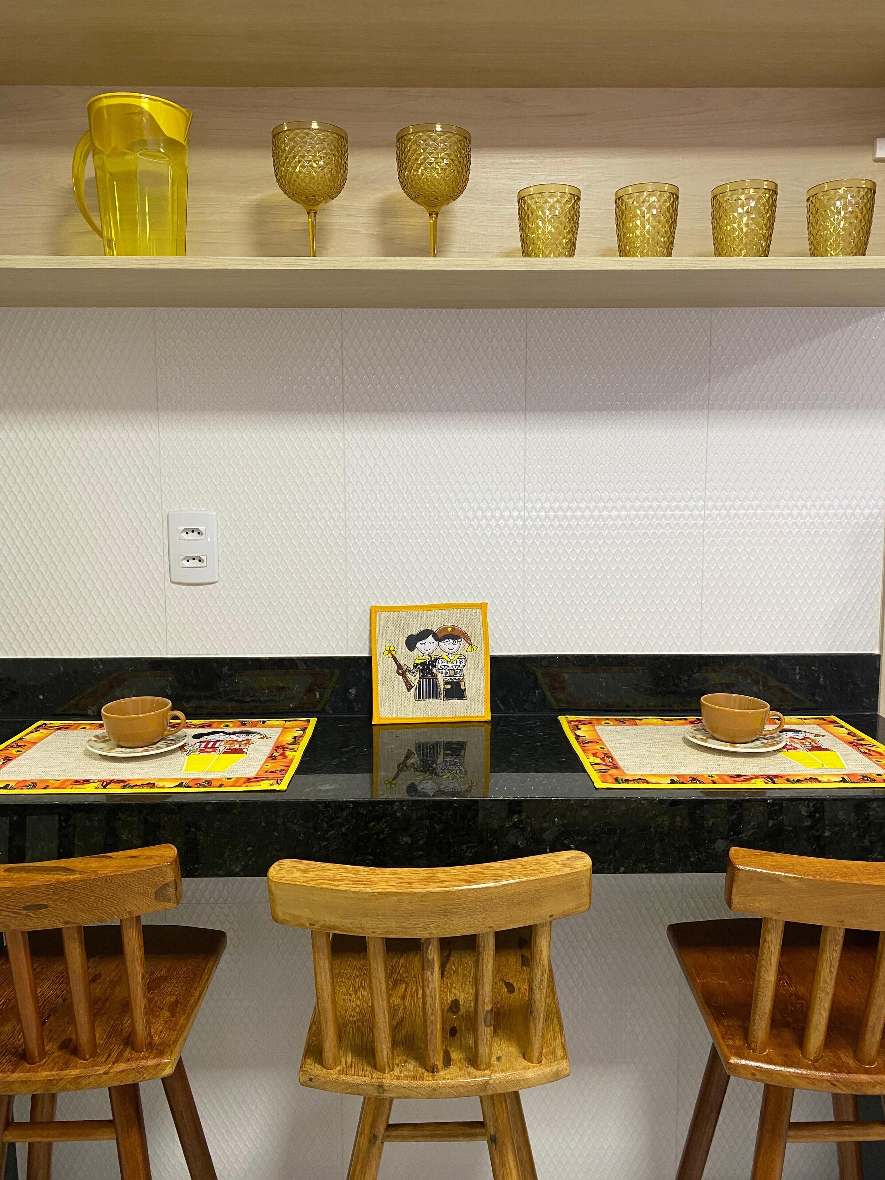 A kitchen with a wooden countertop, a yellow pitcher, and a framed picture on the wall.