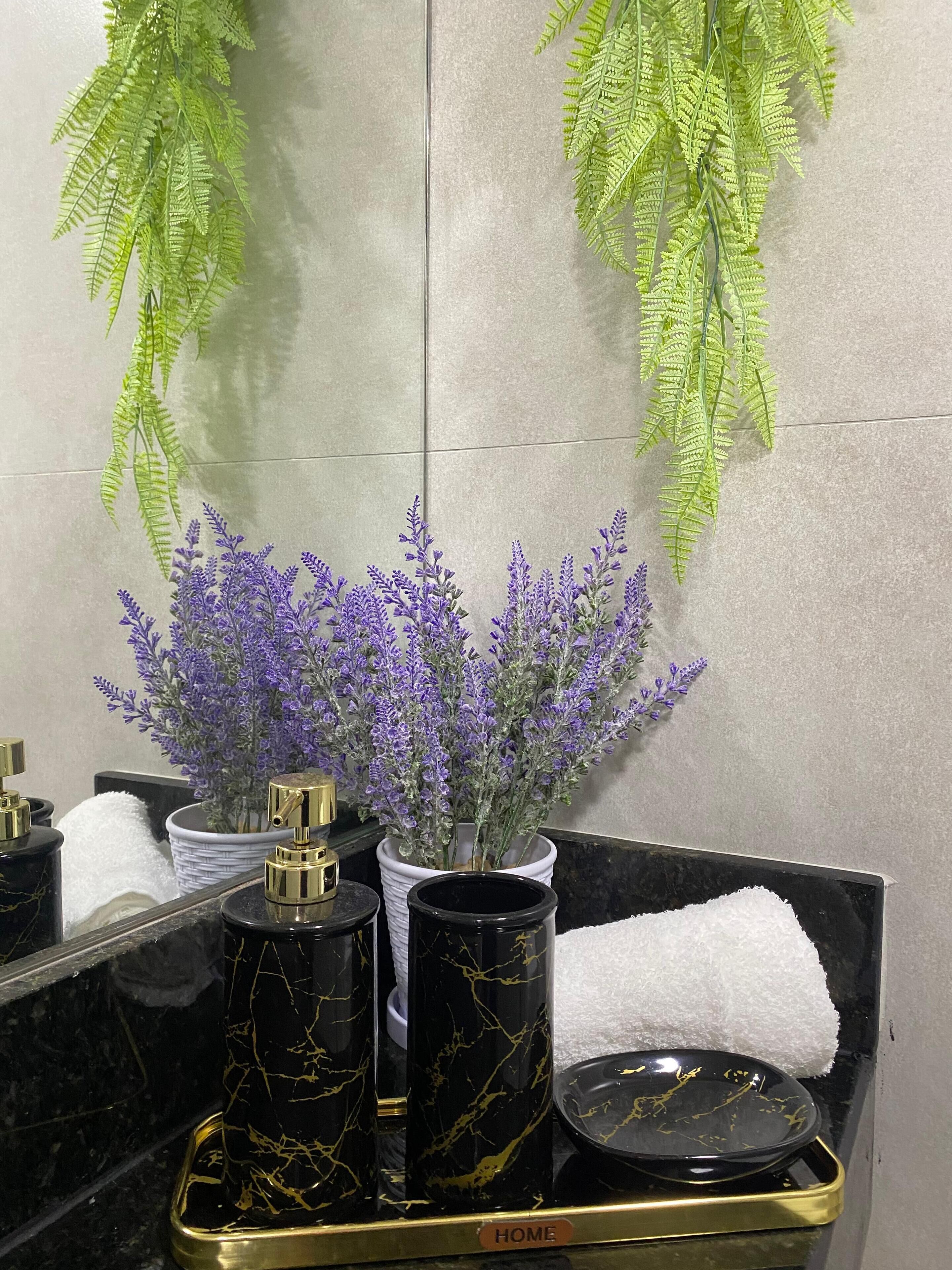 Un meuble-lavabo de salle de bain avec un miroir, des accessoires en marbre noir et un pot de lavande.