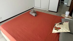 A bedroom with a large bed, a painting on the wall, and a wardrobe.
