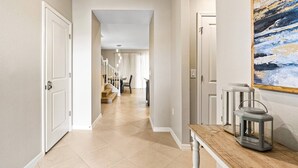 Un pasillo con puertas blancas, un banco de madera y un cuadro en la pared.