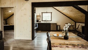 A dining area with a wooden table, chairs, and a view of the kitchen. - Waterfront lux loft 2 bedroom perfect for couples (Pontiac)
