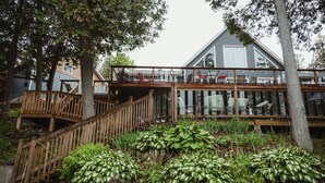 A house with a wooden deck, glass railings, and a staircase leading to a second level. - Waterfront lux loft 2 bedroom perfect for couples (Pontiac)