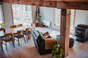 Un salon chaleureux avec une table à manger en bois, un canapé noir et un poêle à bois.