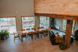 Un salon spacieux avec une table et des chaises de salle à manger en bois, un canapé en cuir noir et une cheminée.