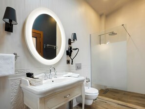 A modern bathroom with a round mirror, a white sink, a toilet, and a glass-enclosed shower. - Villa Polonez (Beykoz)
