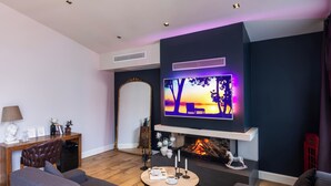 Un salon moderne doté d’une cheminée, d’un grand téléviseur à écran plat et de sièges confortables.