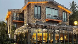 Un bâtiment moderne avec une façade en pierre, de grandes fenêtres et un espace extérieur aménagé avec des sièges.