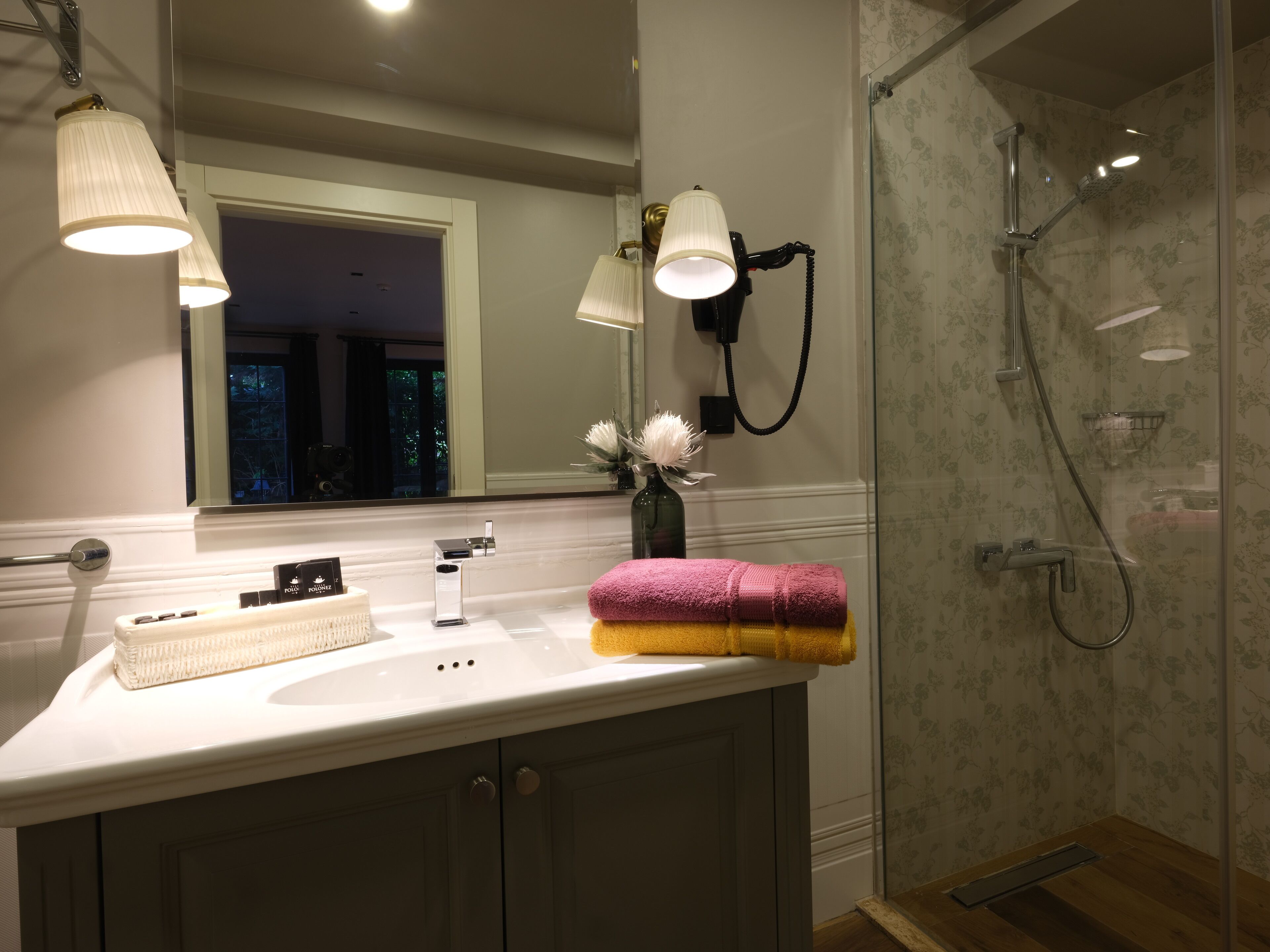 A modern bathroom with a large mirror, a sink, and a shower area.