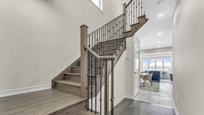 Eine Treppe mit Holzdielen und Metallgeländern, die zu einem Raum mit Essbereich und Ausblick ins Freie führt.