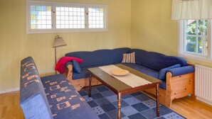 A cozy room with a blue sofa, a wooden table, and a patterned rug. - 2 bedroom lovely home in Ljusterö (Ljusterö)