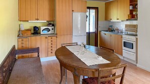 A compact kitchen with wooden cabinets, a microwave, a refrigerator, and a dining table with chairs. - 2 bedroom lovely home in Ljusterö (Ljusterö)