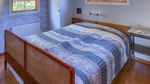 A bedroom with a wooden bed frame, a quilted bedspread, a radiator, a window, and a bedside table with a lamp. - 2 bedroom lovely home in Ljusterö (Ljusterö)