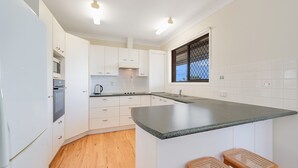 Cozinha moderna com armários brancos, bancada de granito e janela com vista.