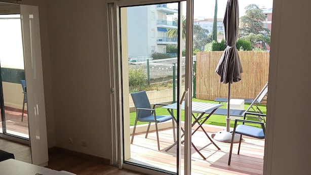 Een moderne kamer met een grote schuifglazen deur die leidt naar een terras.