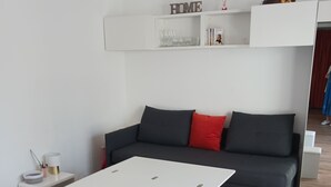 Een moderne woonkamer met een witte bank, rode kussens, een witte salontafel en passende voetenbankjes.