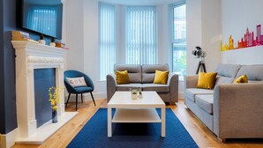 A modern living room with a fireplace, two sofas, a coffee table, and a TV mounted on the wall.