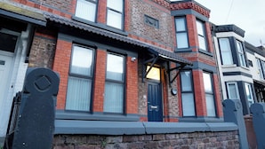A two-story brick building with a dark blue door and windows.