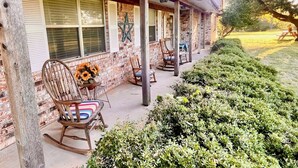 A covered porch with brick walls, wooden rocking chairs, and a star decoration.