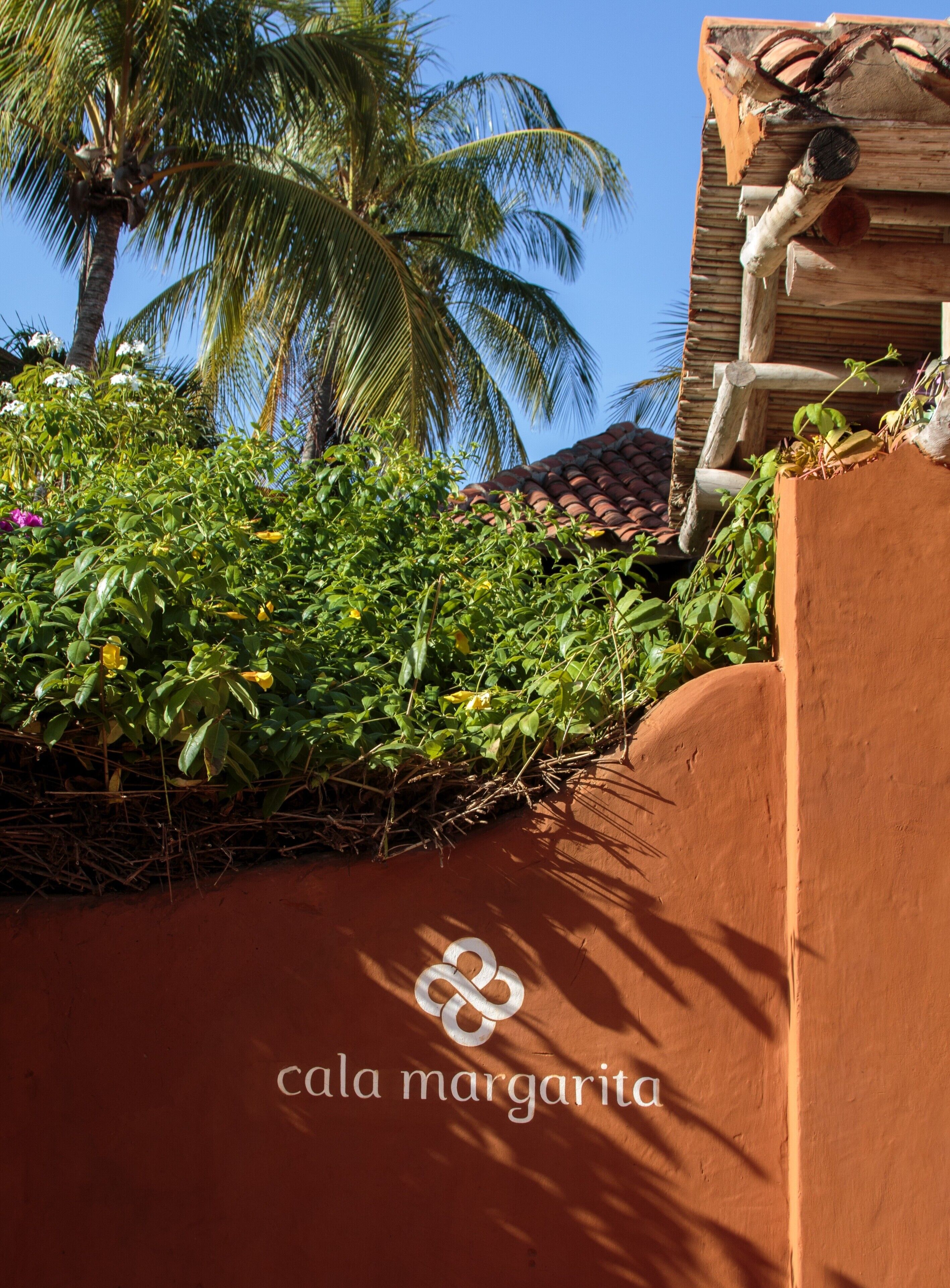 A rustic building with a tiled roof and a palm tree in the background.