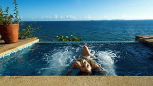 Iemand ontspant in een hottub met uitzicht op de oceaan en bergen.