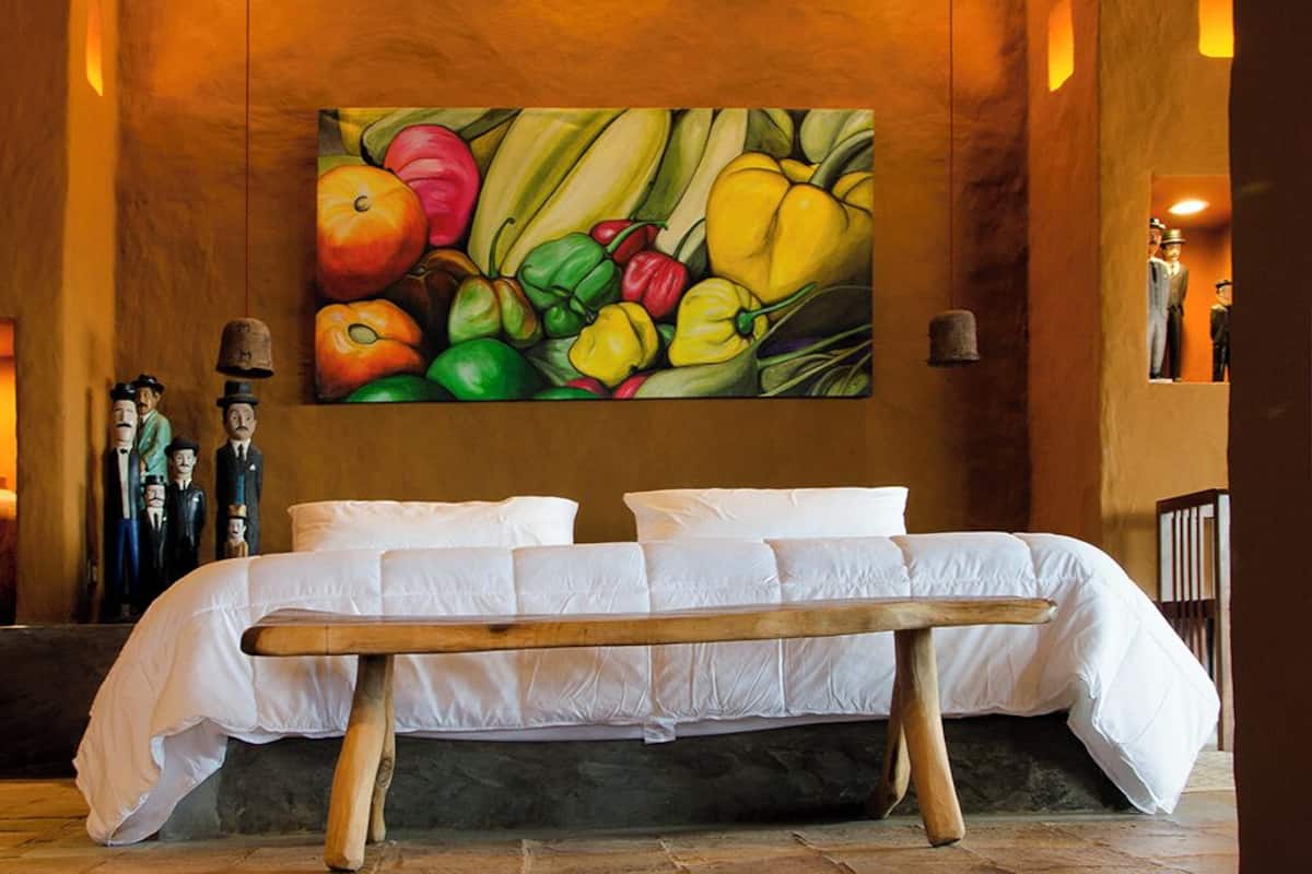 Una habitación con una cama, un cuadro de frutas y verduras, y un techo con macetas.