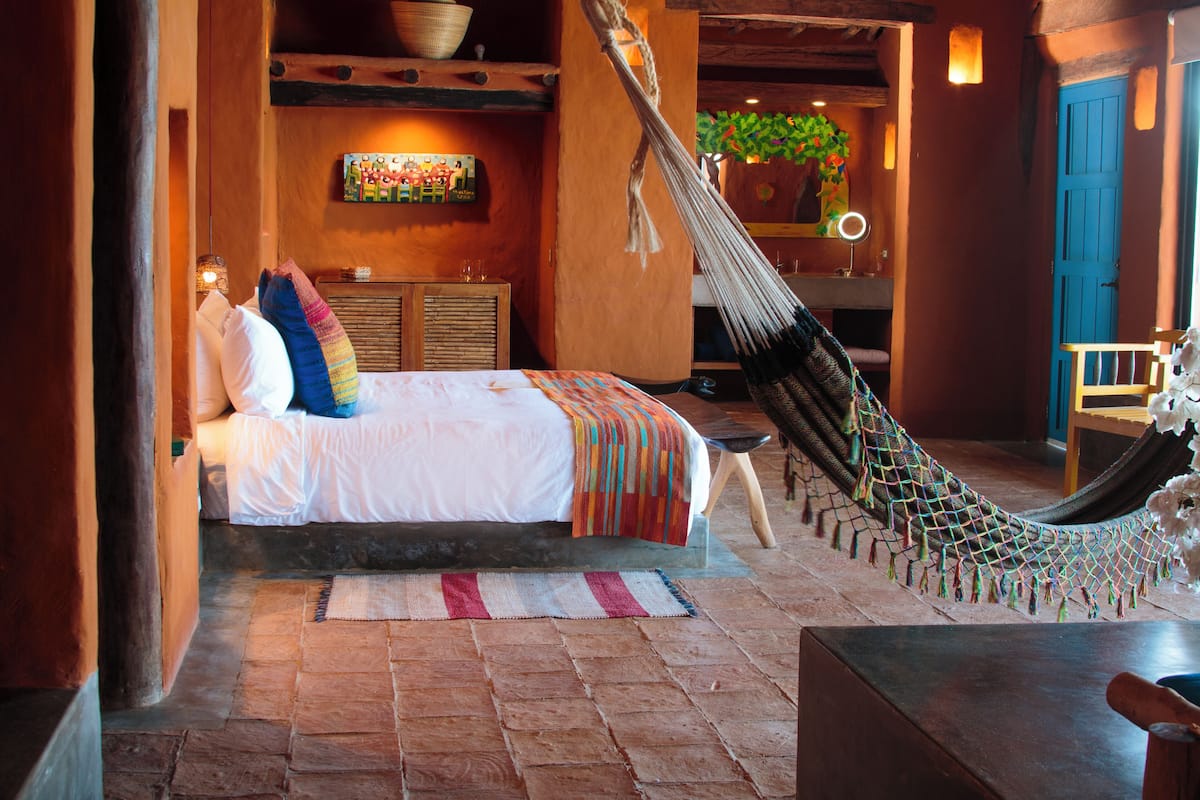 Una habitación acogedora con una cama, una hamaca y suelo de madera.