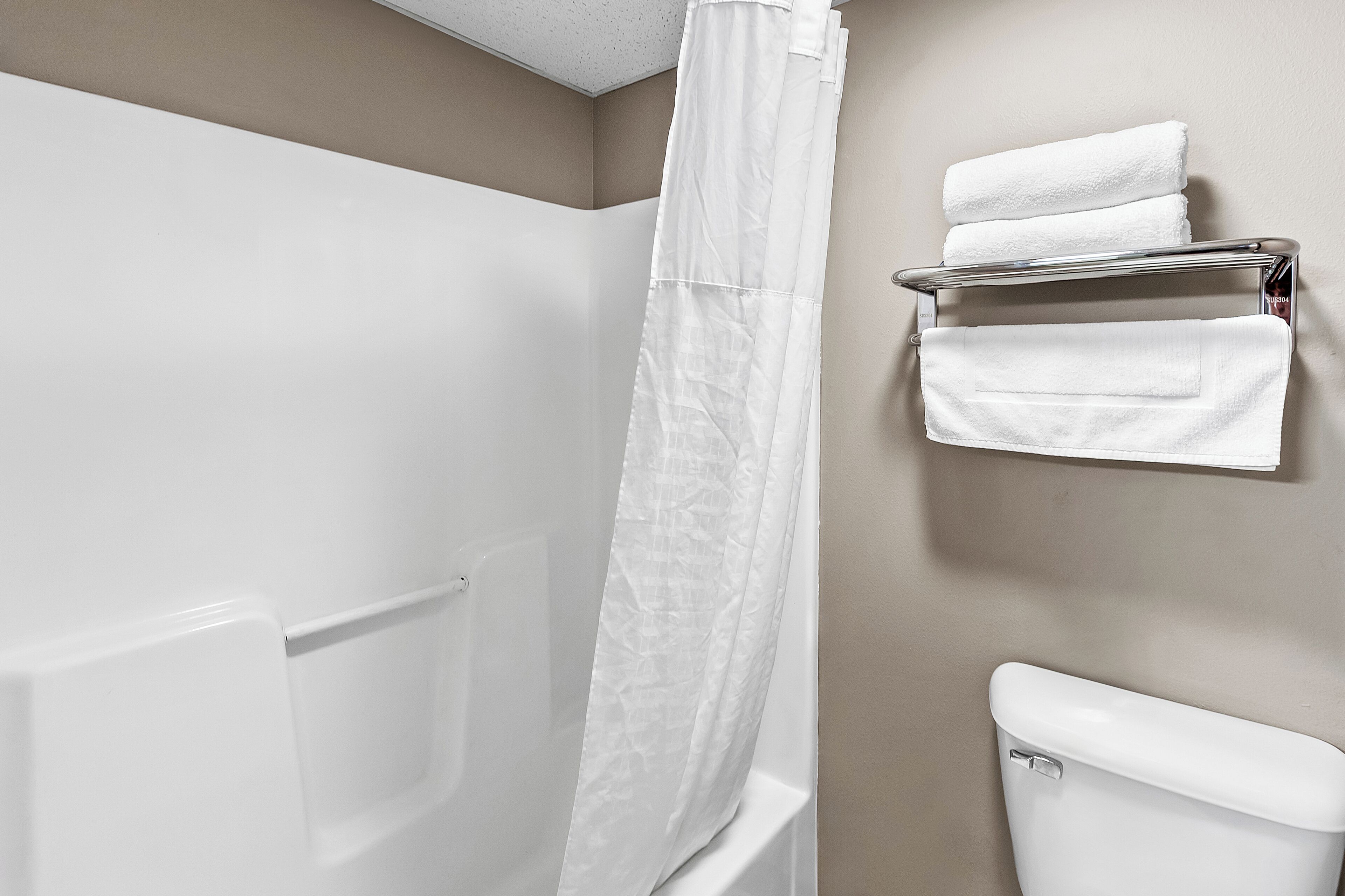 A bathroom with a shower, a toilet, and a towel rack with towels.