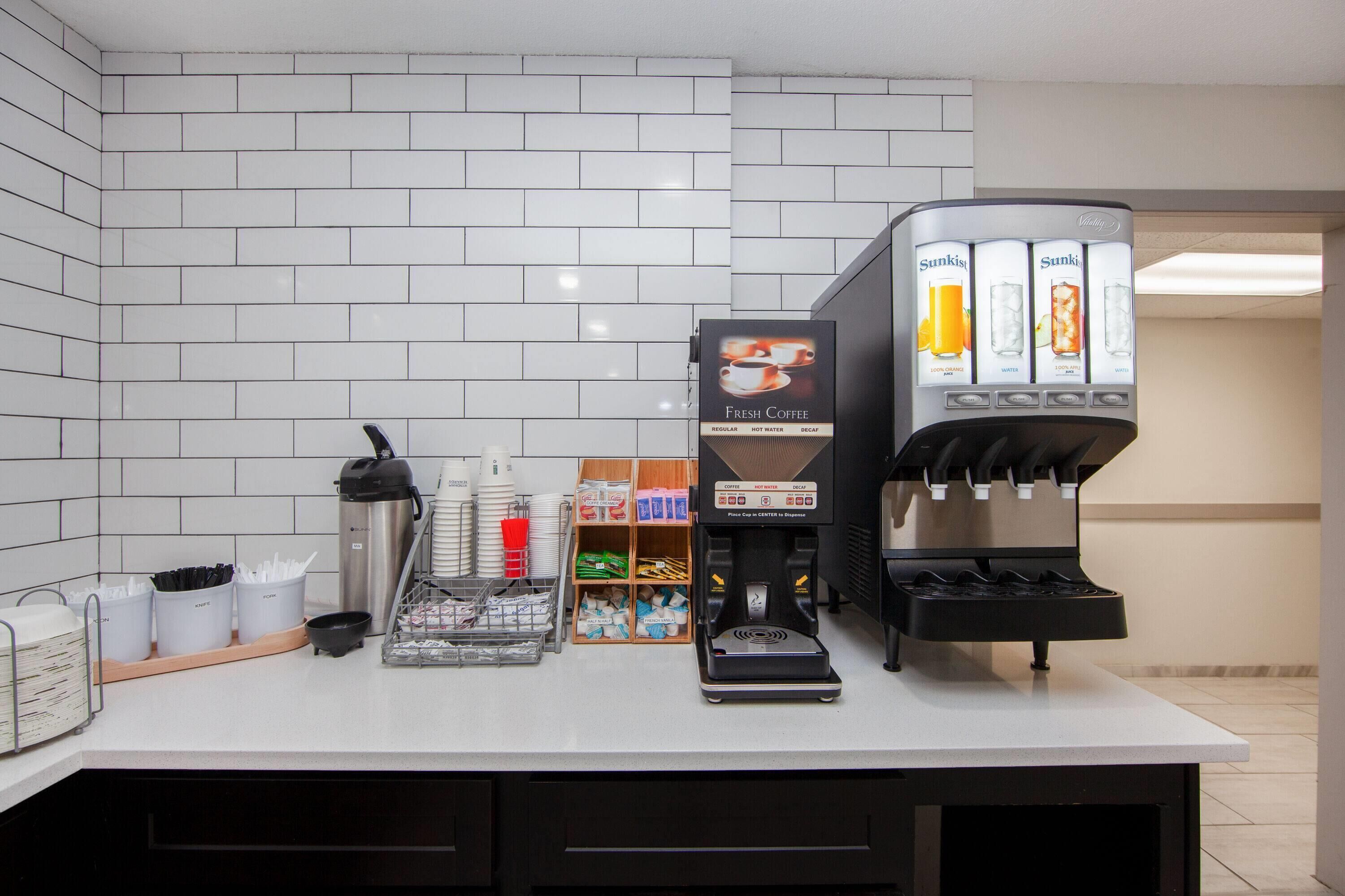 Un espace dédié au café, comprenant une machine à café à l’effigie de la marque, une balance, ainsi qu’une variété de dosettes et de tasses à café.