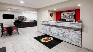 Una cocina moderna con encimera de mármol, pared de acento roja y un logo negro y amarillo en el felpudo.