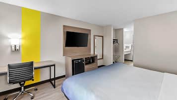 Camera d'albergo con un letto, una scrivania, una sedia, un televisore, un forno a microonde e un armadio.