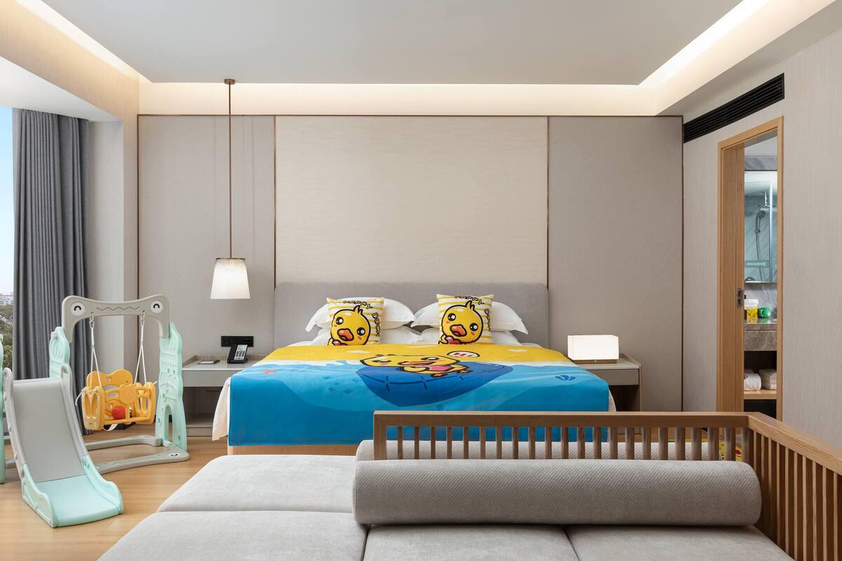 A hotel room with a bed, a desk, a chair, a sofa, and a window.