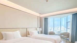 A hotel room with two beds, a desk, a chair, and a large window with a city view. - Wyndham Garden Haikou Meilan (Haikou)