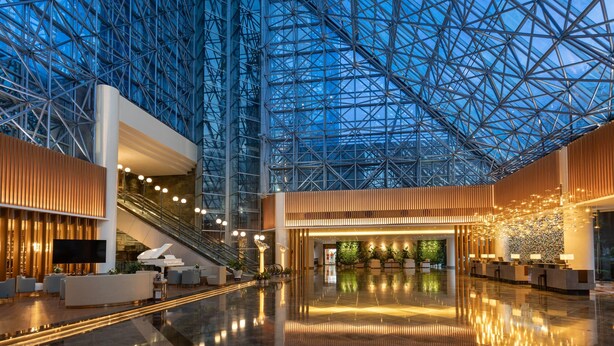 A spacious lobby with a glass ceiling, a reception desk, seating area, and a staircase. - Wyndham Garden Haikou Meilan (Haikou)