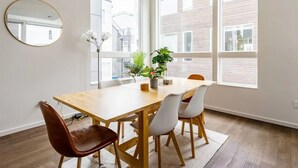 Een moderne eethoek met een houten tafel, witte stoelen en een potplant.