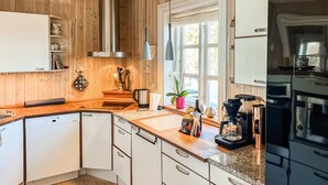 Une cuisine moderne avec des meubles en bois, un four encastré et une machine à café.